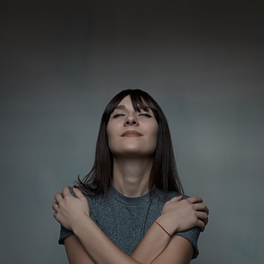 Close up portrait of woman embracing herself